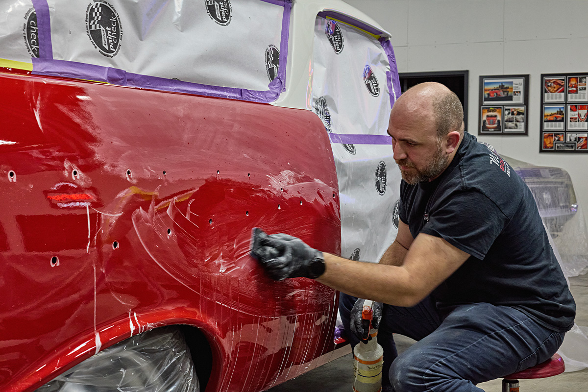 Man using a cleaning solution on the side of a car prepping for trim