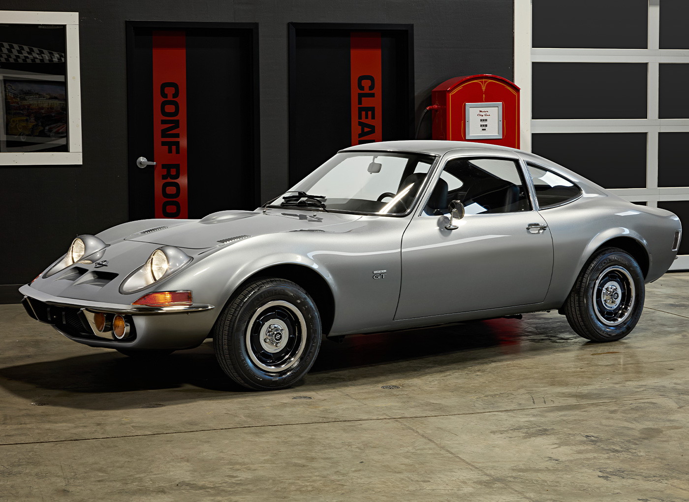 Silver car with headlights on inside the shop